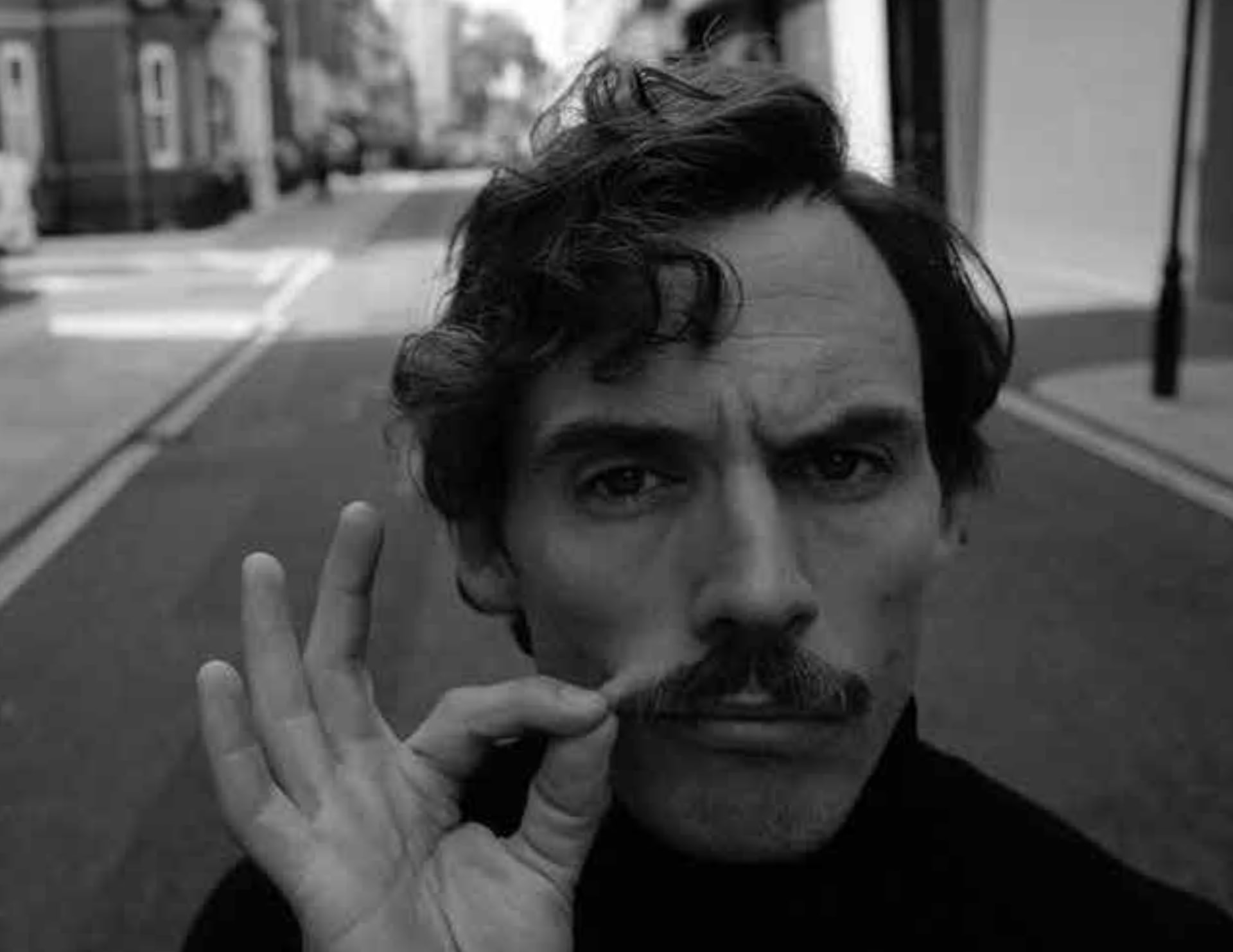 A Mo Bro twirling his moustache on a city street