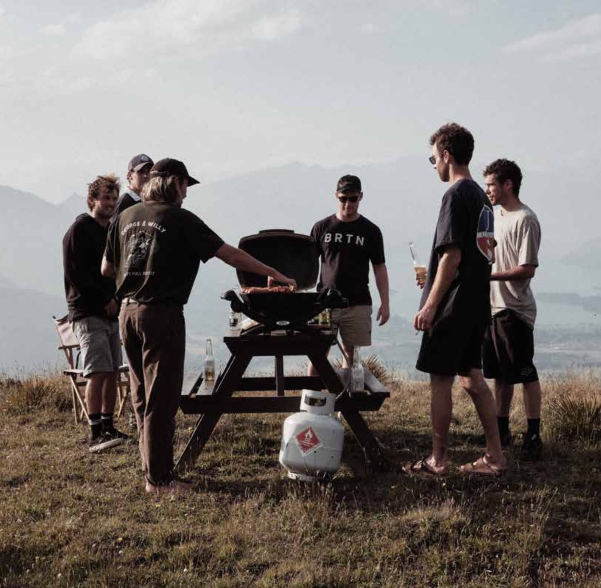 Friends gathered around a barbecue on a hilltop