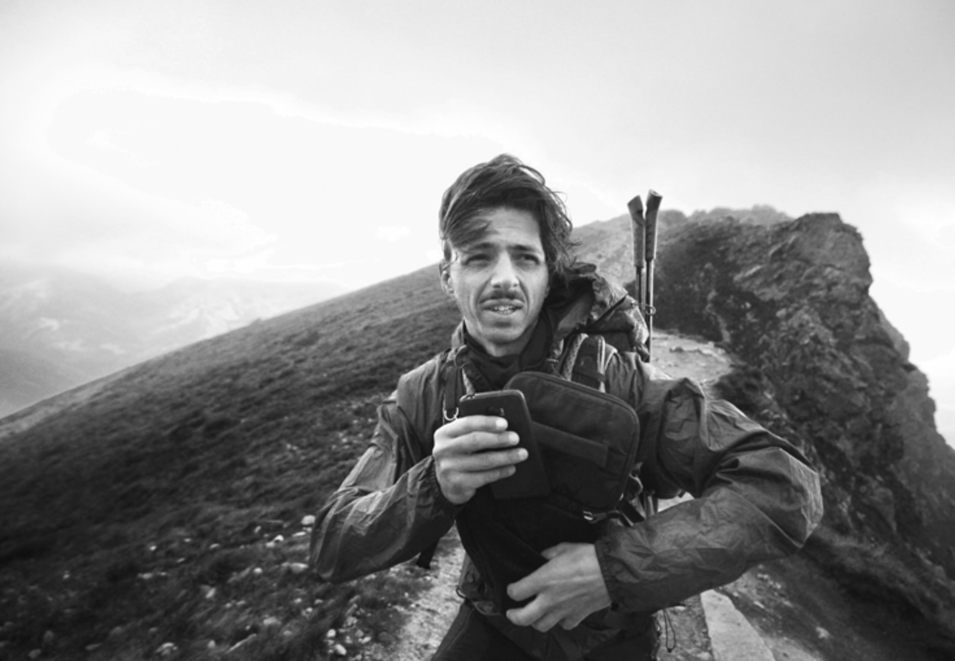 A Mo Bro checking his phone on a mountain ridge
