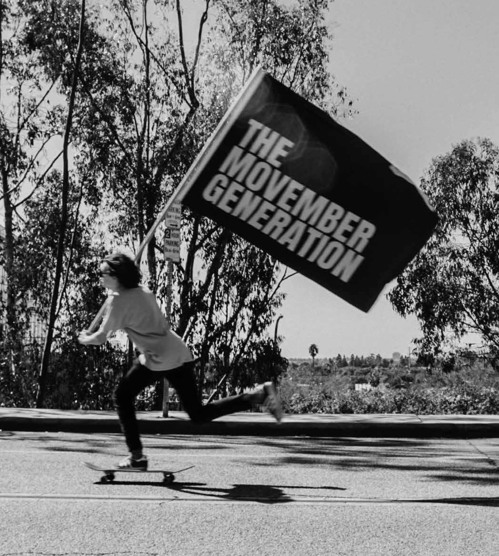 A Mo Bro riding a skateboard while carrying a Movember Generation flag